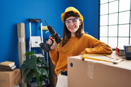 Photo for Young blonde woman wearing hardhat holding drill at new home - Royalty Free Image