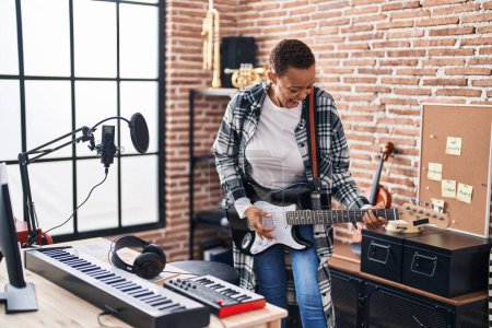 Téléchargez les photos : Africaine américaine musicien souriant confiant jouer de la guitare électrique au studio de musique - en image libre de droit