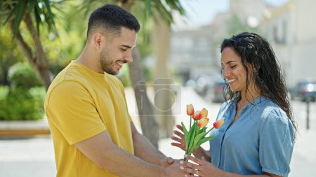 Foto de Hombre y mujer pareja sorpresa con ramo de flores en el parque - Imagen libre de derechos