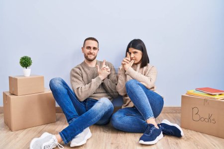 Photo for Young couple moving to a new home holding symbolic gun with hand gesture, playing killing shooting weapons, angry face - Royalty Free Image