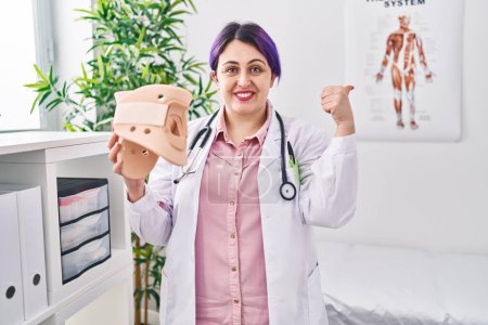 Photo for Plus size doctor woman wit purple hair holding cervical neck collar smiling happy and positive, thumb up doing excellent and approval sign - Royalty Free Image