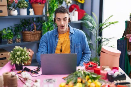 Photo for Handsome hispanic man working at florist shop doing video call scared and amazed with open mouth for surprise, disbelief face - Royalty Free Image