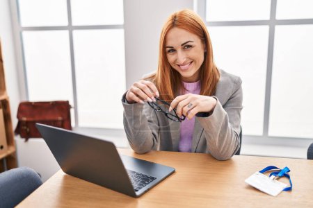 Téléchargez les photos : Jeune femme caucasienne travailleur d'affaires en utilisant des lunettes de tenue d'ordinateur portable au bureau - en image libre de droit