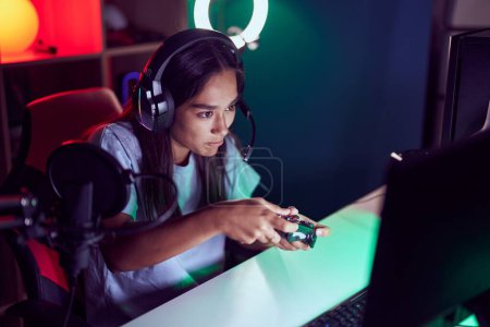 Téléchargez les photos : Young beautiful hispanic woman streamer playing video game using joystick at gaming room - en image libre de droit