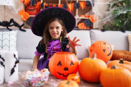 Photo for Adorable hispanic girl having halloween party doing scare gesture at home - Royalty Free Image