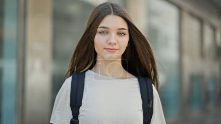 Téléchargez les photos : Jeune belle étudiante portant un sac à dos avec une expression sérieuse à la rue - en image libre de droit