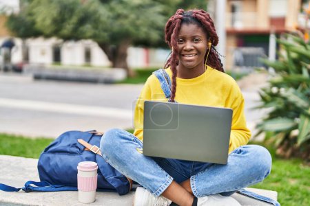 Téléchargez les photos : African american woman student using laptop sitting on bench at campus park - en image libre de droit