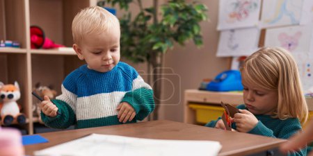 Photo for Adorable boy and girl student cutting paper sitting on table at kindergarten - Royalty Free Image