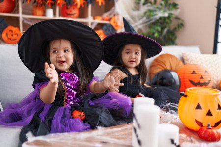 Foto de Adorables chicas gemelas que tienen fiesta de halloween aplaudiendo las manos en casa - Imagen libre de derechos