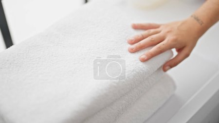 Photo for Young beautiful hispanic woman touching folded towels at laundry room - Royalty Free Image