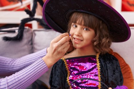 Foto de Adorable chica hispana con disfraz de bruja que tiene maquillaje de Halloween en casa - Imagen libre de derechos