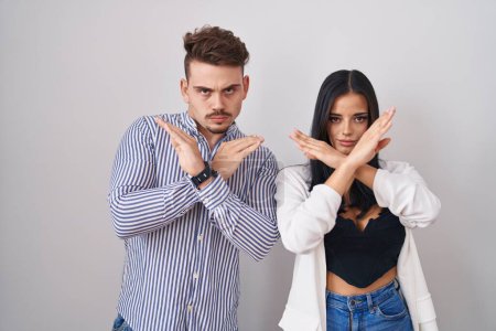 Téléchargez les photos : Jeune couple hispanique debout sur fond blanc expression de rejet croisant les bras faisant signe négatif, visage en colère - en image libre de droit