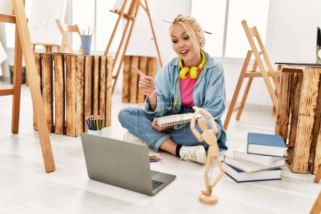 Téléchargez les photos : Young caucasian woman artist having video call sitting on floor at art studio - en image libre de droit