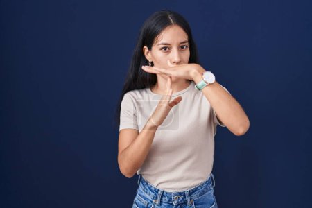 Photo for Young hispanic woman standing over blue background doing time out gesture with hands, frustrated and serious face - Royalty Free Image
