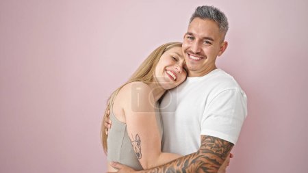 Foto de Hombre y mujer pareja abrazándose sonriendo sobre un fondo rosa aislado - Imagen libre de derechos