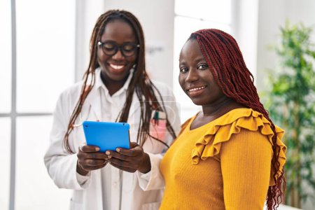 Téléchargez les photos : Médecine afro-américaine et patiente utilisant le pavé tactile ayant une consultation à la clinique - en image libre de droit