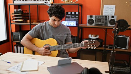 Foto de Joven músico latino que tiene clase de guitarra clásica en línea en el estudio de música - Imagen libre de derechos