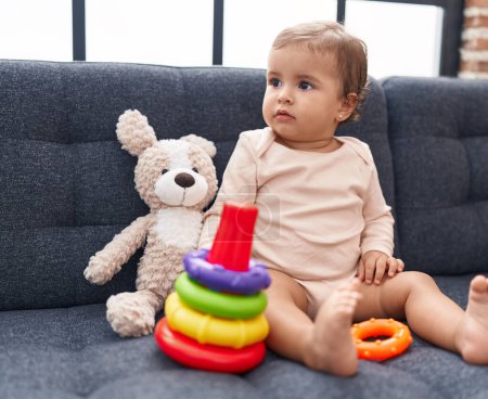 Photo for Adorable hispanic baby playing with hoops game sitting on sofa at home - Royalty Free Image