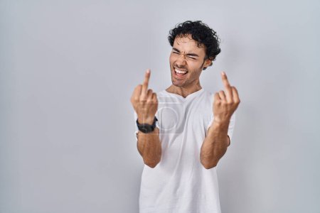 Foto de Hispanic man standing over isolated background showing middle finger doing fuck you bad expression, provocation and rude attitude. screaming excited - Imagen libre de derechos