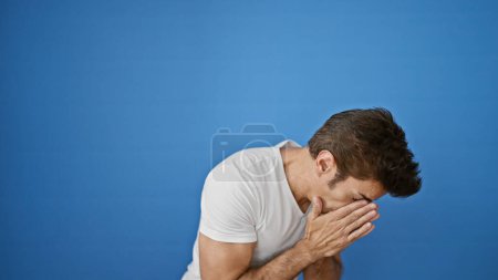 Photo for Young hispanic man sneezing over isolated blue background - Royalty Free Image