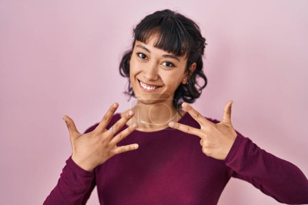 Photo for Young beautiful woman standing over pink background showing and pointing up with fingers number eight while smiling confident and happy. - Royalty Free Image
