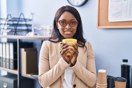 Foto de Trabajadora de negocios afroamericana joven bebiendo café en la oficina - Imagen libre de derechos