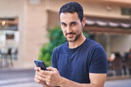Téléchargez les photos : Young hispanic man smiling confident using smartphone at coffee shop terrace - en image libre de droit