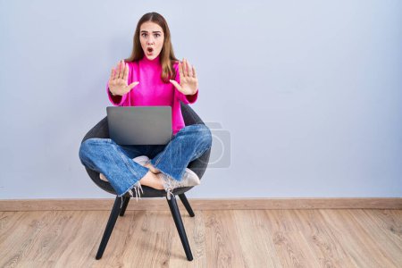 Photo for Young hispanic girl working using computer laptop doing stop gesture with hands palms, angry and frustration expression - Royalty Free Image
