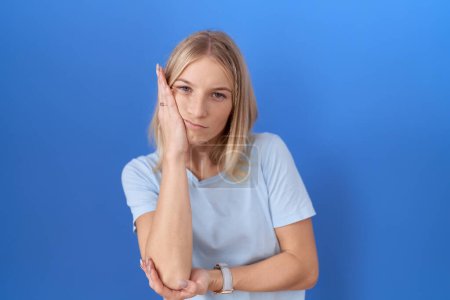 Téléchargez les photos : Jeune femme caucasienne portant casual bleu t-shirt pensée à la recherche fatigué et ennuyé avec des problèmes de dépression avec les bras croisés. - en image libre de droit