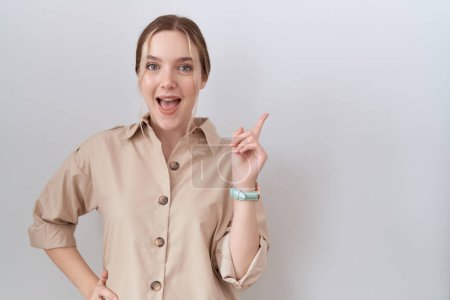 Téléchargez les photos : Jeune femme caucasienne portant une chemise décontractée avec un grand sourire sur le visage, pointant avec le doigt de la main sur le côté en regardant la caméra. - en image libre de droit