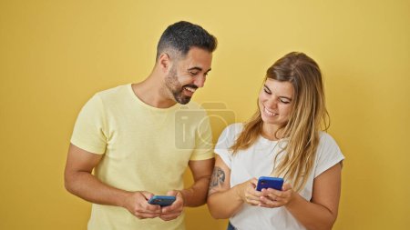 Photo for Man and woman couple smiling confident using smartphones over isolated yellow background - Royalty Free Image