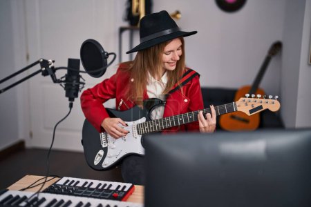 Téléchargez les photos : Jeune femme blonde musicienne chantant une chanson jouant de la guitare électrique au studio de musique - en image libre de droit