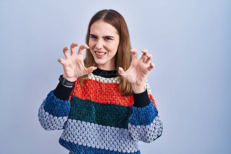 Photo for Young hispanic girl standing over blue background smiling funny doing claw gesture as cat, aggressive and sexy expression - Royalty Free Image