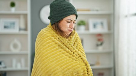 Photo for Young beautiful hispanic woman feeling cold covered with blanket at home - Royalty Free Image