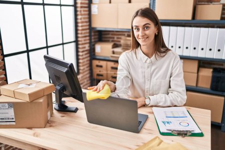 Téléchargez les photos : Young caucasian woman ecommerce business worker cleaning laptop at office - en image libre de droit