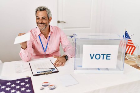 Téléchargez les photos : Moyen-âge homme aux cheveux gris président de table électorale tenant papier de vote au collège électoral - en image libre de droit