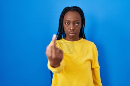 Photo for Beautiful black woman standing over blue background showing middle finger, impolite and rude fuck off expression - Royalty Free Image