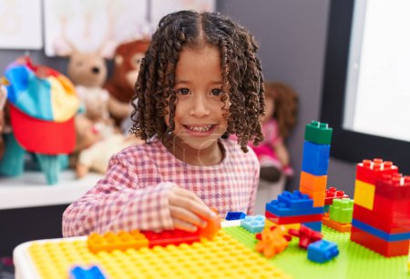 Photo for African american girl playing with construction blocks sitting on table at kindergarten - Royalty Free Image