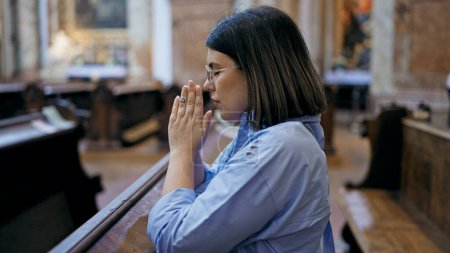 Photo for Young beautiful hispanic woman praying on a church bench at St. Karl Borromus church - Royalty Free Image