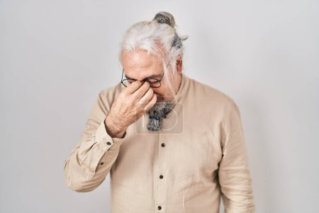 Photo for Middle age man with grey hair standing over isolated background tired rubbing nose and eyes feeling fatigue and headache. stress and frustration concept. - Royalty Free Image