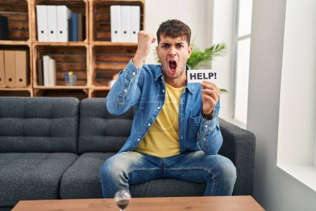 Photo for Young hispanic man at therapy asking for help annoyed and frustrated shouting with anger, yelling crazy with anger and hand raised - Royalty Free Image
