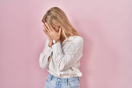 Photo for Young caucasian woman wearing casual white shirt over pink background with sad expression covering face with hands while crying. depression concept. - Royalty Free Image