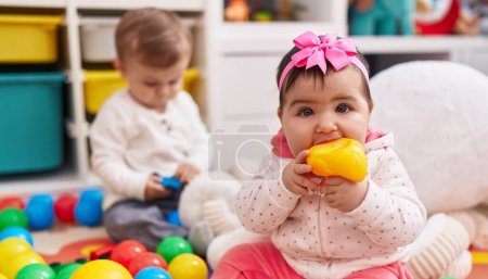Téléchargez les photos : Adorable garçon et fille jouer avec des boules sucer jouet de canard à la maternelle - en image libre de droit