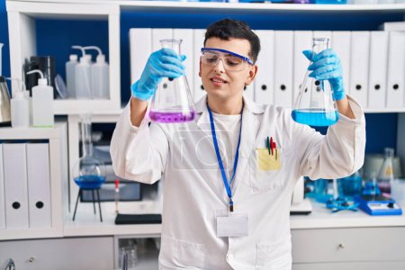 Téléchargez les photos : Young non binary man scientist smiling confident measuring liquid at laboratory - en image libre de droit