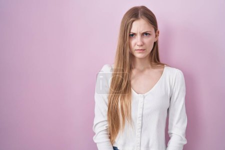 Foto de Mujer caucásica joven de pie sobre fondo rosa escéptico y nervioso, frunciendo el ceño molesto debido a un problema. persona negativa. - Imagen libre de derechos