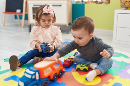 Photo for Adorable boy and girl playing with cars toy sitting on floor at kindergarten - Royalty Free Image