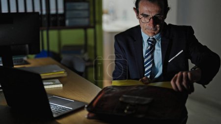 Photo for Middle age man business worker sitting on table starting to work at the office - Royalty Free Image