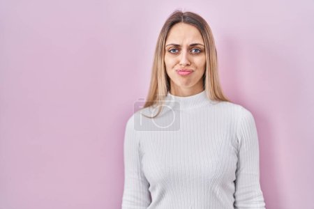 Photo for Young blonde woman wearing white sweater over pink background depressed and worry for distress, crying angry and afraid. sad expression. - Royalty Free Image