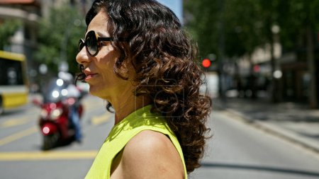 Foto de Mujer hispana de mediana edad caminando cruzando la calle peatonal en la calle - Imagen libre de derechos