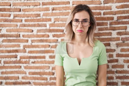 Photo for Young beautiful woman standing over bricks wall depressed and worry for distress, crying angry and afraid. sad expression. - Royalty Free Image